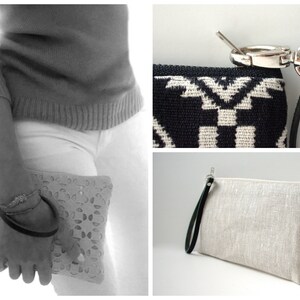 May include: Three different styles of clutches. The first is a black and white geometric patterned clutch with a black leather strap. The second is a white crocheted clutch with a black leather strap. The third is a light beige linen clutch with a black leather strap.