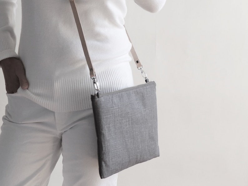 Model holding gray linen crossbody bag with adjustable leather strap.