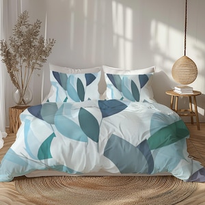 以下が含まれることがあります： 白い掛け布団カバーと2つのお揃いの枕カバーが付いたベッド。寝具は、青とターコイズの葉の形が重なり合った模様です。部屋は、織りのラグと木製のサイドテーブルを備えたニュートラルなカラーパレットです。