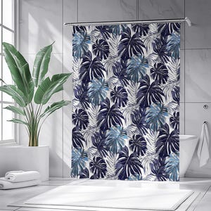 Könnte beinhalten: Ein Duschvorhang mit tropischem Blättermuster in Marine-, Blau- und Grautönen auf weißem Hintergrund. Der Vorhang hängt in einem modernen Badezimmer mit einer weißen Badewanne und einer großen Topfpflanze.