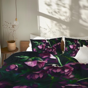 May include: Bedding set with a dark background and a watercolour floral design in purple and pink. The set includes a duvet cover and two pillowcases, creating a cohesive and artistic bedroom aesthetic.