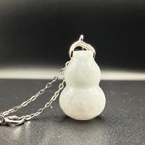 May include: A white gourd-shaped pendant necklace. The pendant is made of a translucent, light-colored stone and is suspended from a delicate silver chain. The gourd has a smooth, rounded shape.