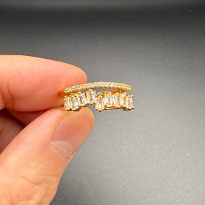 Könnte beinhalten: Goldring mit einem zarten Band und einer Reihe von baguetteförmigen, klaren Steinen.