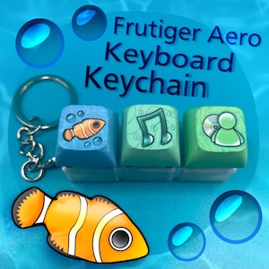 Könnte beinhalten: Ein Frutiger Aero-Tastatur-Schlüsselanhänger mit drei farbigen Tastenkappen: ein Fisch, Noten und eine Person mit einer CD. Der Schlüsselanhänger hat einen silbernen Ring und eine Kette. Der Hintergrund ist ein blaues Wasser-Thema mit Blasen.