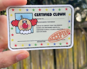 May include: A rectangular sticker with a cartoon clown illustration and the text "CERTIFIED CLOWN". The sticker has a border of colorful stars and the word "ACCEPTED" stamped on it. The text includes "ISSUED TO", "DATE OF BIRTH: YESTERDAY", and "SIGNATURE".