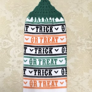 May include: White kitchen towel with a green crocheted hanging loop. The towel has alternating orange and green stripes with the text "Trick or Treat" repeated on each stripe.