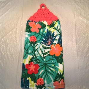 May include: A pink crocheted hanging loop on a white kitchen towel with a tropical floral print featuring hibiscus flowers and green leaves.