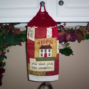 May include: Red crocheted kitchen towel holder with a white towel featuring a house with the word "HOPE" and the text "All that you can imagine..."