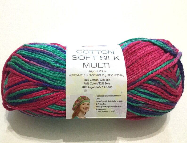 May include: A skein of Cotton Soft Silk Multi yarn in a pink, green, and purple color combination. The yarn is 126 yards and 2.5 ounces. The label states that the yarn is 78% cotton and 22% silk.