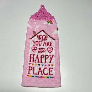 May include: Pink kitchen towel with a crocheted hanging loop. The towel features a white house with a red heart and the text "You are my happy place".