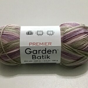 May include: A ball of Premier Garden Batik yarn in shades of purple, green, and beige. The label indicates it is a light weight yarn, with 284 yards (260 meters) and 3.5 ounces (100 grams).