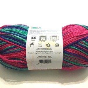 May include: A skein of yarn in a pink, green, and blue color pattern. The yarn is labeled "Stained Glass" and is made in Turkey. The label includes care instructions for hand washing and laying flat to dry.