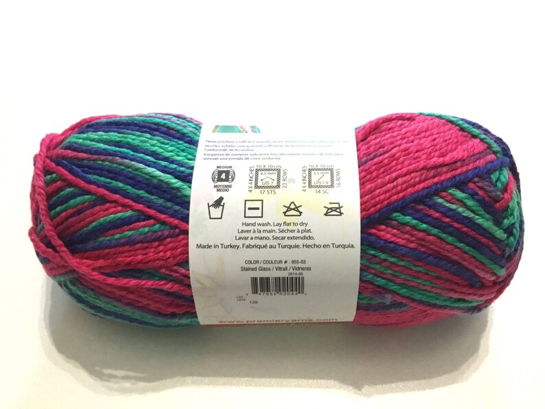 May include: A skein of yarn in a pink, green, and blue color pattern. The yarn is labeled "Stained Glass" and is made in Turkey. The label includes care instructions for hand washing and laying flat to dry.