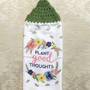 May include: White kitchen towel with a green crocheted hanging loop. The towel features a floral wreath with the text "PLANT good THOUGHTS" in pink and black.