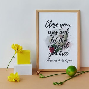 May include: A framed print with a watercolor background and the quote "Close your eyes and let the music set you free - Phantom of the Opera".