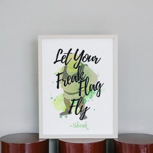 Puede incluir: Una impresión enmarcada en blanco con un fondo de acuarela verde que presenta un ogro de dibujos animados. La impresión dice "Let your freak flag fly" con el texto "Shrek" en la parte inferior.