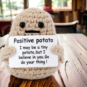 May include: A crocheted potato toy holding a sign that says "Positive potato I may be a tiny potato, but I believe in you. Go do your thing!"