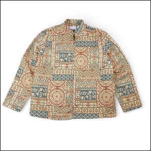 Puede incluir: Chaqueta beige con cremallera completa y mangas largas. La chaqueta presenta un patrón repetitivo de formas geométricas en tonos marrón, verde azulado y rojo. El cuello es de estilo alzado. La chaqueta está hecha de tela tejida.