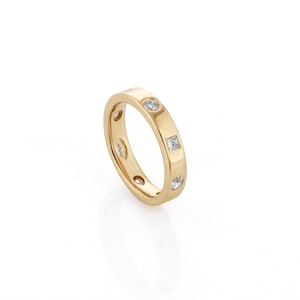 May include: A yellow gold band ring featuring a series of flush-set gemstones. The stones alternate between round and square shapes, embedded directly into the smooth, polished surface of the metal band, creating a clean and uniform appearance.