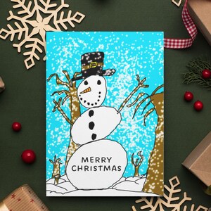 May include: A Christmas card featuring a whimsical snowman illustration. The snowman has a black top hat, a carrot nose, and coal eyes and buttons. The card has the words "MERRY CHRISTMAS" on the bottom. The background is light blue with falling snow.