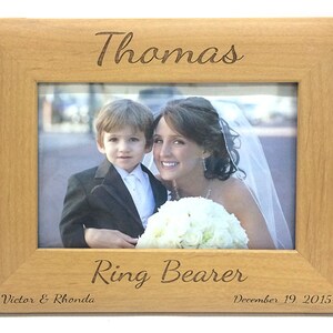 May include: A wooden picture frame with the inscription "Thomas Ring Bearer Victor & Rhonda December 19, 2015". The frame has a photo of a young boy in a tuxedo and a woman in a wedding dress.