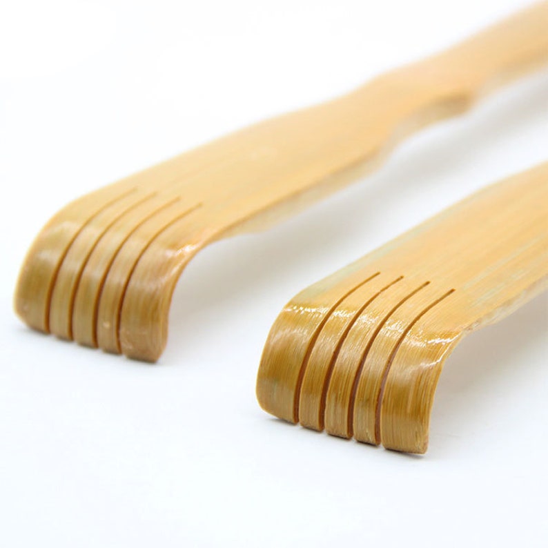 May include: Two wooden back scratchers with curved handles and five rows of teeth. The scratchers are made of natural bamboo and have a light brown color.