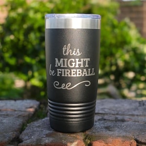 Op de afbeelding: Een zwarte roestvrijstalen tumbler met een witte inscriptie die "this might be fireball" luidt met een decoratieve swirl eronder.