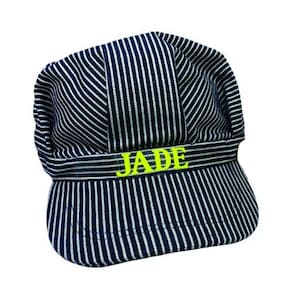 May include: A blue and white striped engineer's cap with a yellow "JADE" name embroidered on the front.