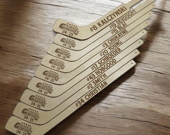 May include: A set of ten wooden hockey sticks with the Richmond Generals logo and player numbers. The sticks are arranged in a fan shape, with the top stick being the most prominent.