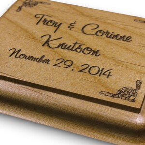 May include: A wooden box with an engraved inscription that reads "Troy & Corrine Knutson November 29, 2014". The box has a decorative design in the corners.