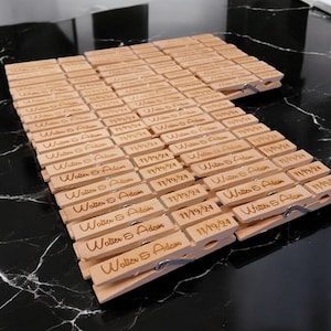 May include: A group of wooden clothespins with the text "Walter & Adam 11/19/24" engraved on each one.