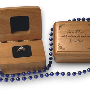 May include: A wooden box with a ring inside and a blue beaded necklace. The box is engraved with the message "You are all I need and I want to be with you forever I Love You!"