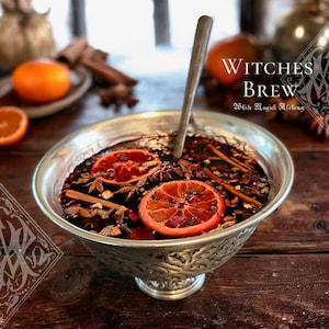 May include: A silver bowl filled with a dark liquid, garnished with orange slices, star anise, and cinnamon sticks. A wooden spoon rests in the brew. The text "Witches Brew" is visible in the background.