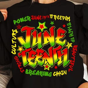 May include: Black sweatshirt with a colourful graphic design that says "Juneteenth" in a graffiti style. The graphic also includes the words "Power June 19th Freedom Strong Culture Breaking Chain Black is Beautiful".