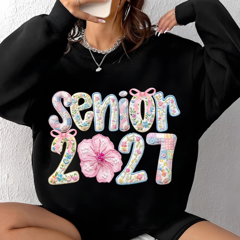 Puede incluir: Sudadera negra con la palabra "Senior 2021" en un dise&ntilde;o floral y patchwork. La palabra "Senior" est&aacute; en un patr&oacute;n floral azul claro y blanco, y los n&uacute;meros "2021" est&aacute;n en un dise&ntilde;o patchwork.