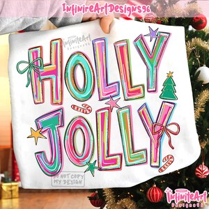 May include: A white t-shirt featuring the colorful text HOLLY JOLLY in bright pink, teal, and yellow outlines. The design includes a green Christmas tree, two red and white candy canes, a green bow, a red bow, and several small stars.