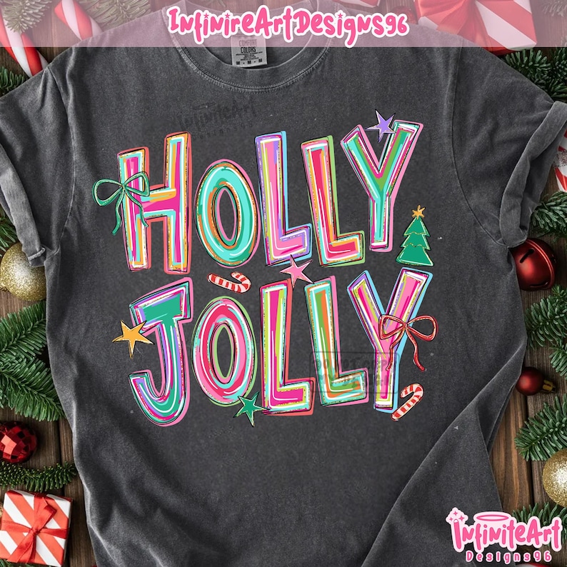 May include: A charcoal gray short-sleeve t-shirt featuring the text HOLLY JOLLY in large, colorful, multi-layered block letters. The design includes small graphic elements such as a green bow, a green Christmas tree, stars, and candy canes.