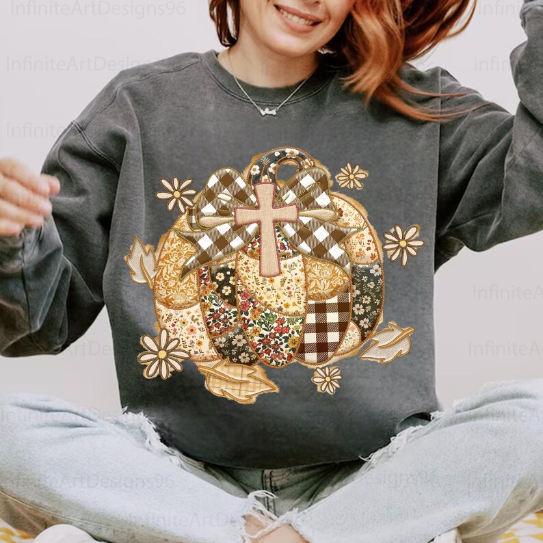 Puede incluir: Sudadera gris oscuro con un dise&ntilde;o de calabaza de retazos, una cruz y un lazo. La calabaza tiene patrones florales y a cuadros, con acentos de margaritas y hojas. El texto "InfiniteArtDesigns96" es visible.