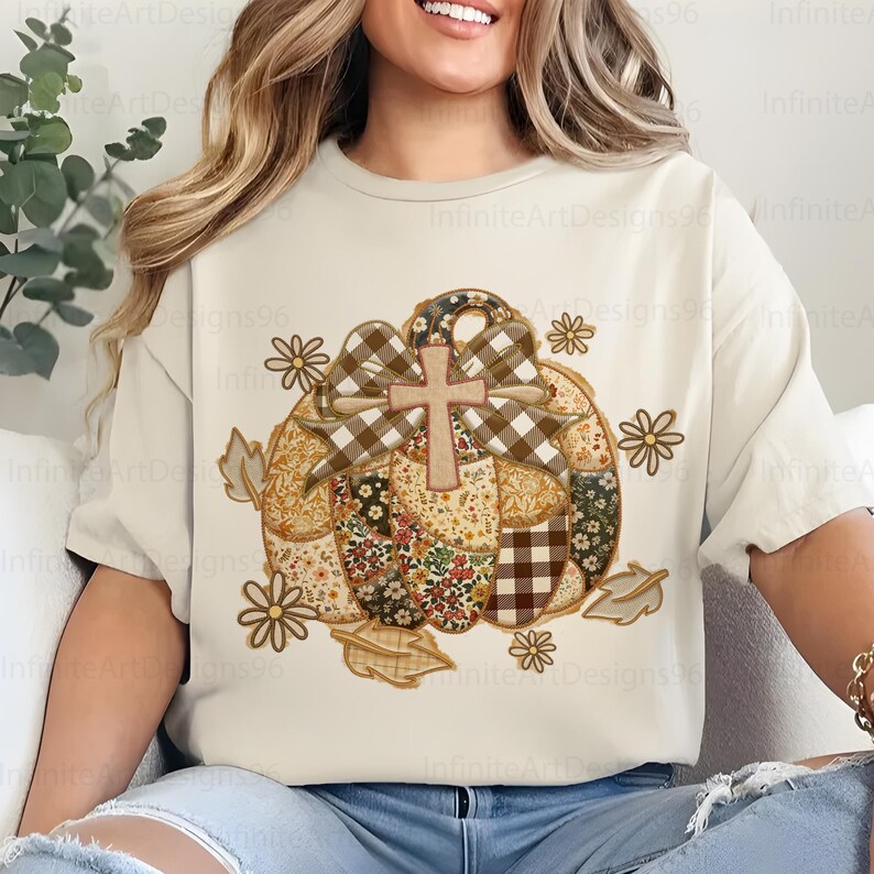 Puede incluir: Camiseta color crema con un dise&ntilde;o de calabaza de retazos, una cruz, un lazo y detalles florales y de hojas. La calabaza est&aacute; compuesta por varias telas estampadas. El texto "Infinite Art Designs96" es visible.