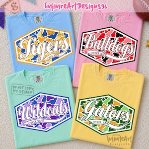 Op de afbeelding: Vier T-shirts met korte mouwen in lichtblauw, roze, mintgroen en geel. Elk shirt heeft een zeshoekige afbeelding met een camouflagepatroon en witte tekst in scriptstijl met de woorden Tigers, Bulldogs, Wildcats of Gators en School Name.