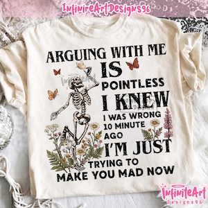 May include: A cream-colored t-shirt featuring a black graphic of a skeleton dancing among wildflowers and butterflies. The text reads: ARGUING WITH ME IS POINTLESS I KNEW I WAS WRONG 10 MINUTE AGO I'M JUST TRYING TO MAKE YOU MAD NOW in black lettering.