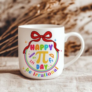 May include: White ceramic mug with a rainbow design and the text "Happy Pi Day be irrational". The design includes a large pi symbol, a ruler, a protractor, and the number 3.14.