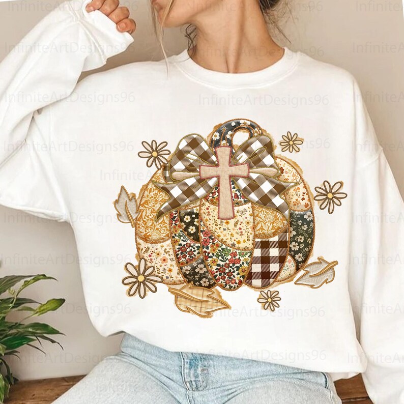 Puede incluir: Sudadera blanca con un dise&ntilde;o de calabaza de retazos, una cruz, un lazo y detalles florales y de hojas. La calabaza est&aacute; compuesta por varios patrones, incluyendo florales, cuadros y colores lisos. El dise&ntilde;o incluye el texto "Infinite Art Designs96".