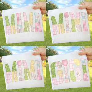 May include: Four white t-shirts, each held by a hand, feature colourful patchwork lettering. The shirts display the words "MAMA", "MINI", "MIMI", and "GIGI" in green, pink, yellow, and blue patterned fabric.