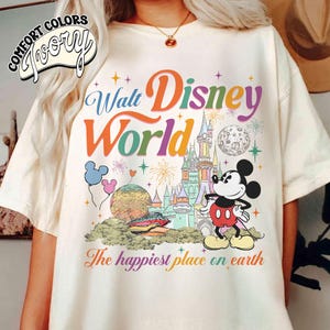 May include: A white ceramic mug with a black handle and the text "But First, Coffee" in a handwritten style. The mug is on a white surface. The mug is likely for hot beverages.