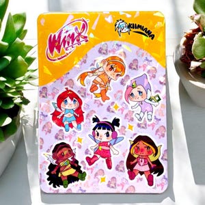 Peut inclure: Une planche d'autocollants rectangulaire avec des personnages de fées de dessins animés du Winx Club. La feuille a une bordure jaune avec le logo Winx Club et le texte "Kiimiana". Le fond est violet clair avec de petites illustrations de fées.