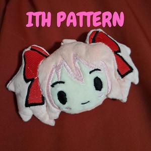 Può includere: Un giocattolo di peluche rosa e bianco con fiocchi rossi e tratti del viso ricamati. Il giocattolo ha il testo "ITH PATTERN" sopra.