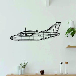 May include: A black metal airplane wall art piece. The artwork depicts the side profile of a small aircraft, with detailed lines outlining the fuselage, wings, and tail. The piece is mounted on a white wall, creating a modern, minimalist aesthetic.