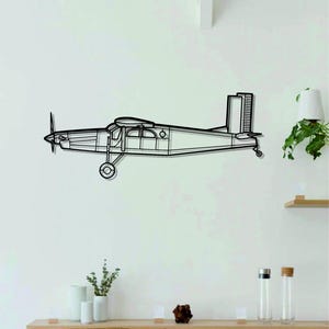 May include: A black metal airplane wall art piece. The airplane is a side profile with a propeller, windows, and tail. The art is mounted on a white wall, with a shelf below holding decorative items.