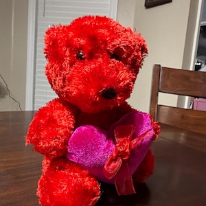 May include: A white ceramic mug with a black handle and the text "But First, Coffee" in a black, bold font. The mug is sitting on a wooden surface. The mug is approximately 4 inches tall.